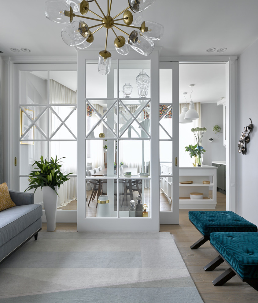 На фото: гостиная комната в стиле неоклассика (современная классика) с белыми стенами и светлым паркетным полом с