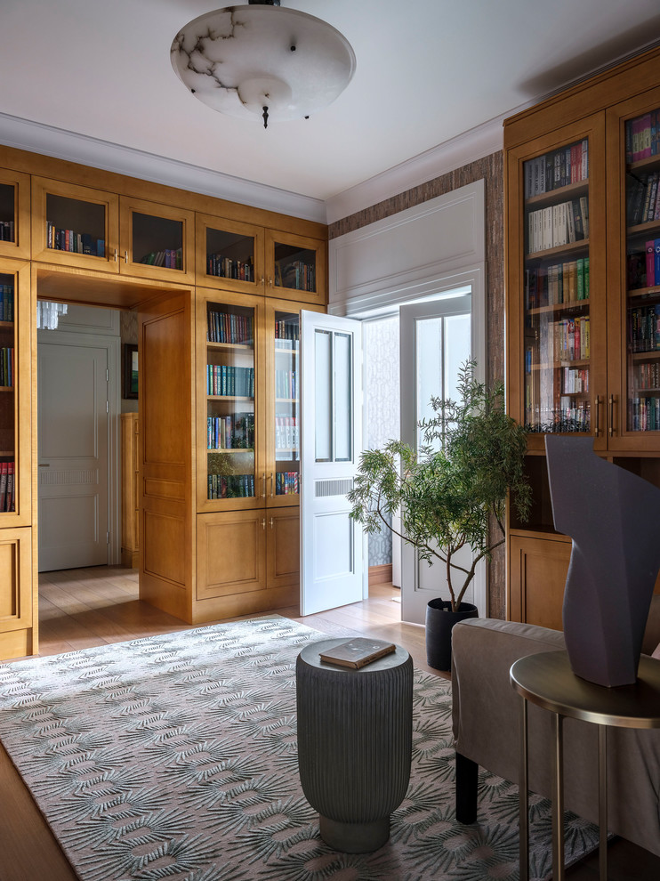 На фото: изолированная гостиная комната среднего размера в стиле неоклассика (современная классика) с с книжными шкафами и полками, серыми стенами, паркетным полом среднего тона, коричневым полом и ковром на полу с