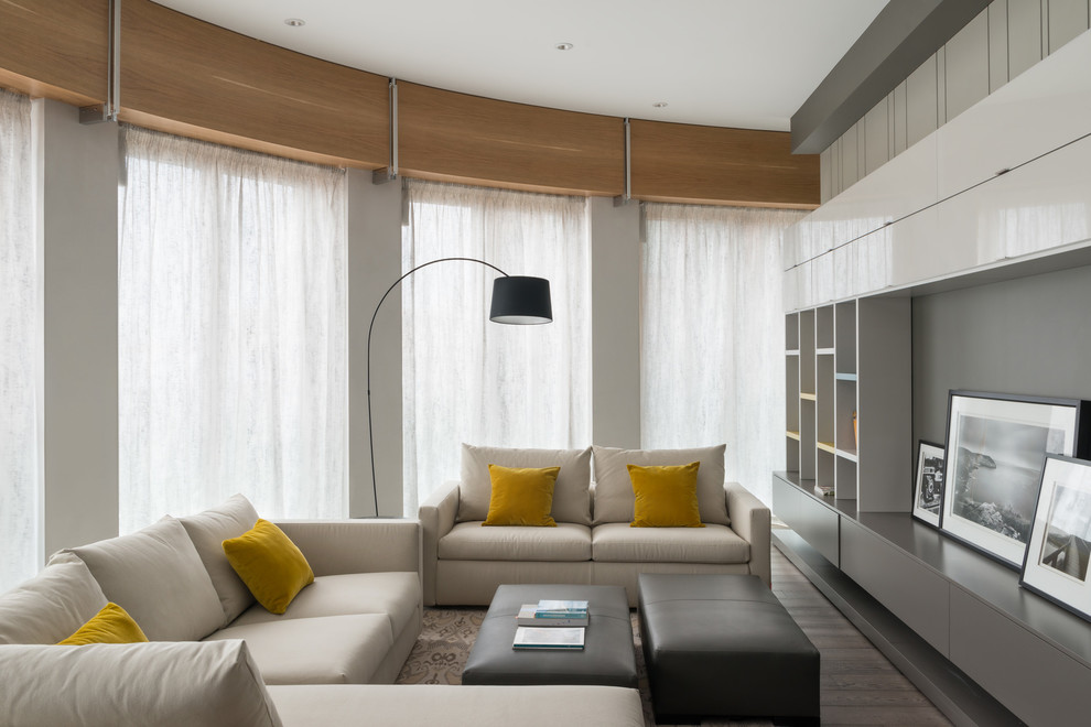 Источник вдохновения для домашнего уюта: большая парадная, открытая гостиная комната в современном стиле с серыми стенами, паркетным полом среднего тона, серым полом и телевизором на стене