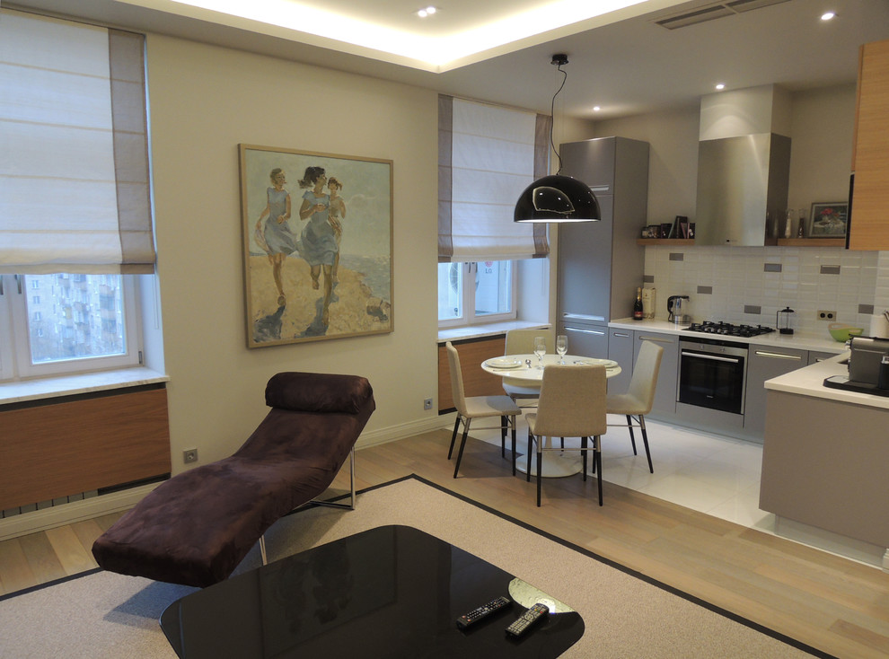 Стильный дизайн: открытая, объединенная гостиная комната среднего размера в современном стиле с с книжными шкафами и полками, серыми стенами, паркетным полом среднего тона и серым полом без камина - последний тренд