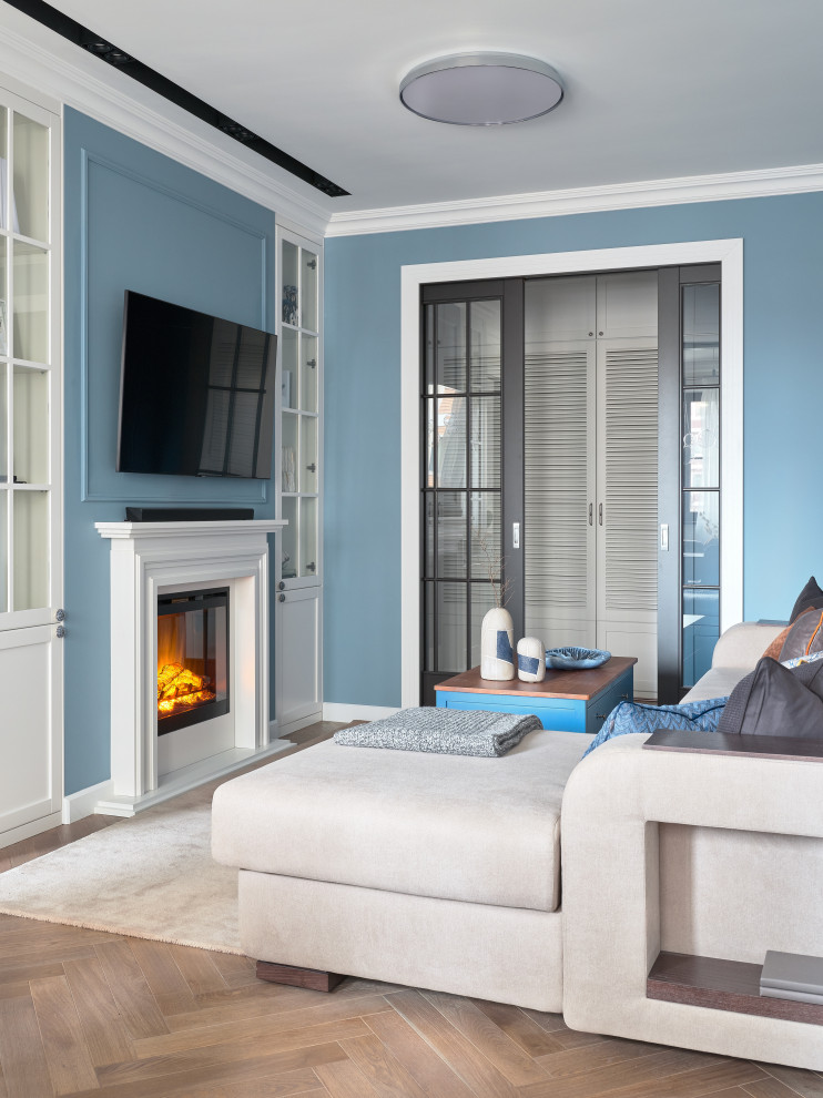 Пример оригинального дизайна: гостиная комната в современном стиле с синими стенами, паркетным полом среднего тона, стандартным камином, телевизором на стене и коричневым полом