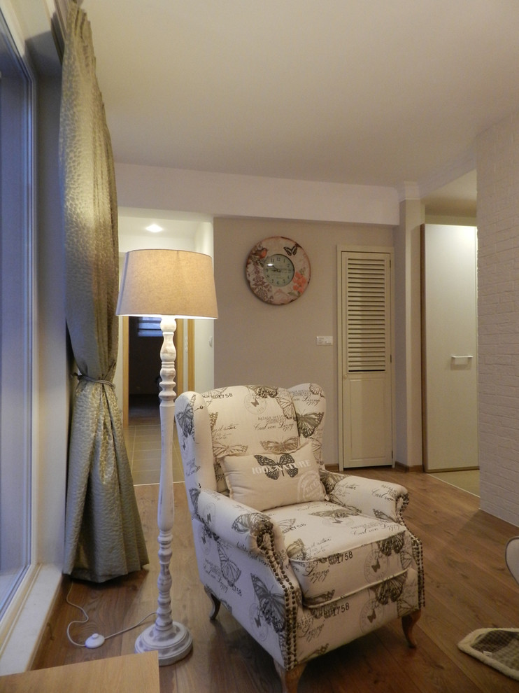 Пример оригинального дизайна: маленькая открытая гостиная комната в стиле шебби-шик с серыми стенами, отдельно стоящим телевизором, полом из ламината и коричневым полом для на участке и в саду