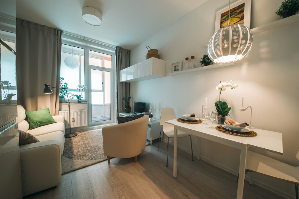 Идея дизайна: маленькая гостиная комната в скандинавском стиле с белыми стенами и полом из ламината для на участке и в саду