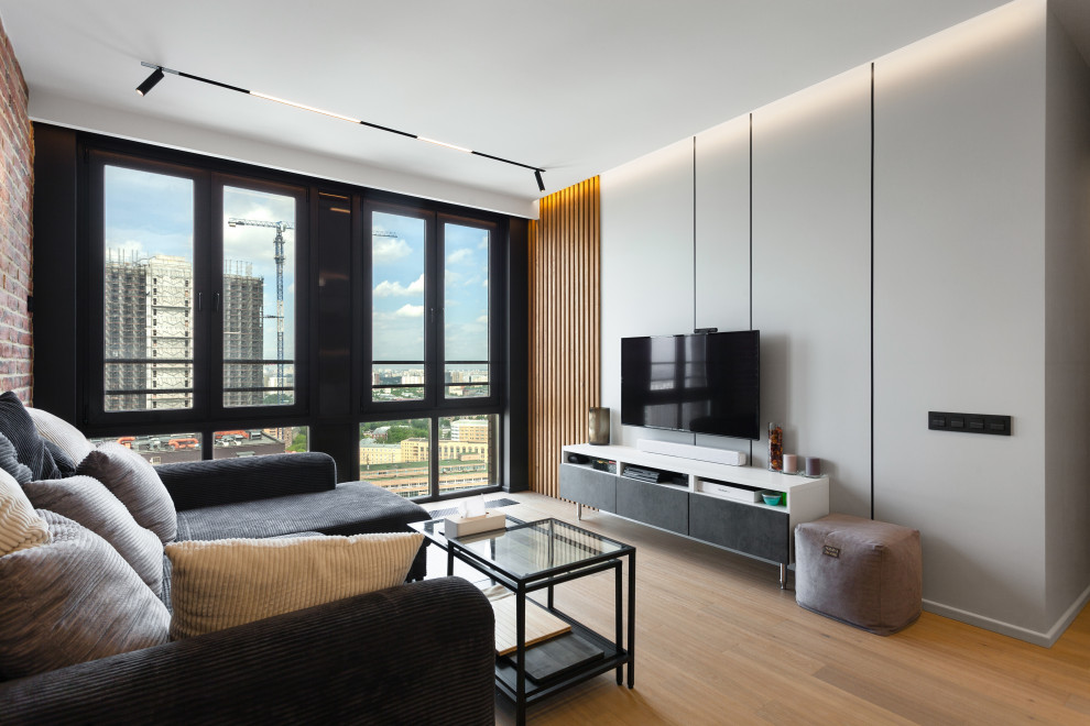 На фото: объединенная гостиная комната среднего размера в современном стиле с белыми стенами, полом из ламината, телевизором на стене, бежевым полом, многоуровневым потолком и панелями на части стены