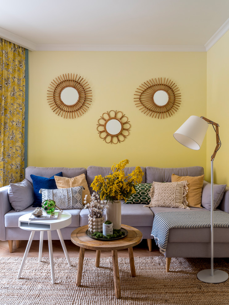 Aménagement d'un salon gris et jaune bord de mer de taille moyenne avec un mur jaune, aucune cheminée et parquet clair.