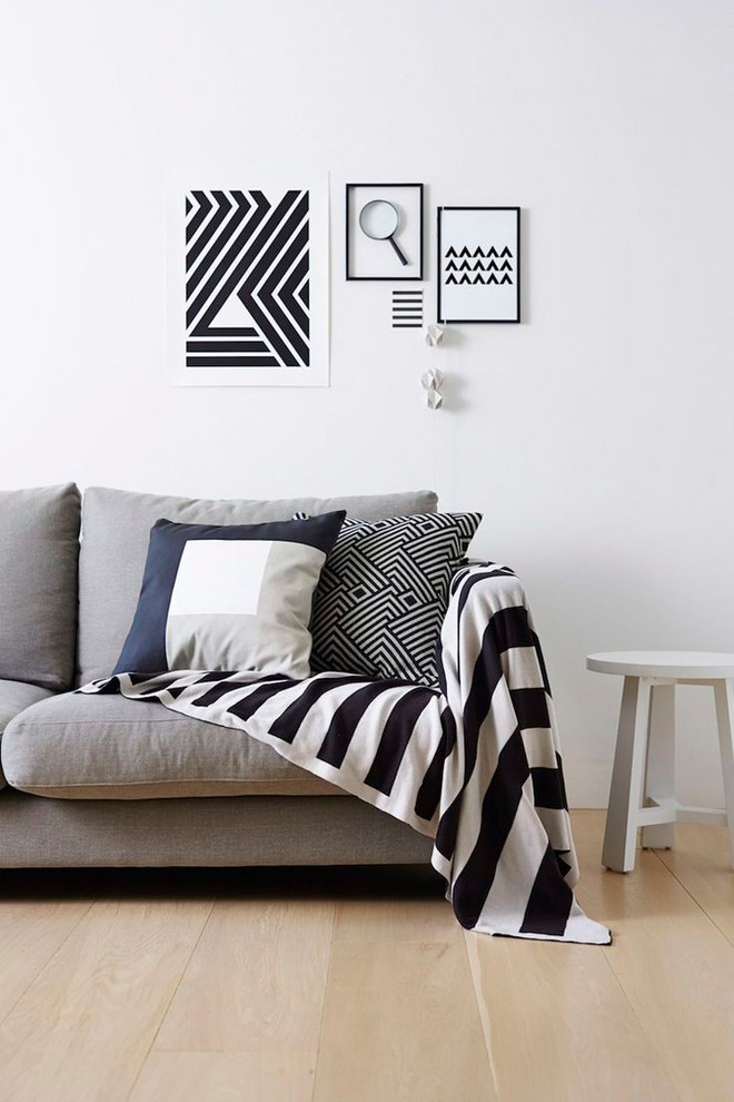 На фото: гостиная комната в скандинавском стиле с белыми стенами и светлым паркетным полом с