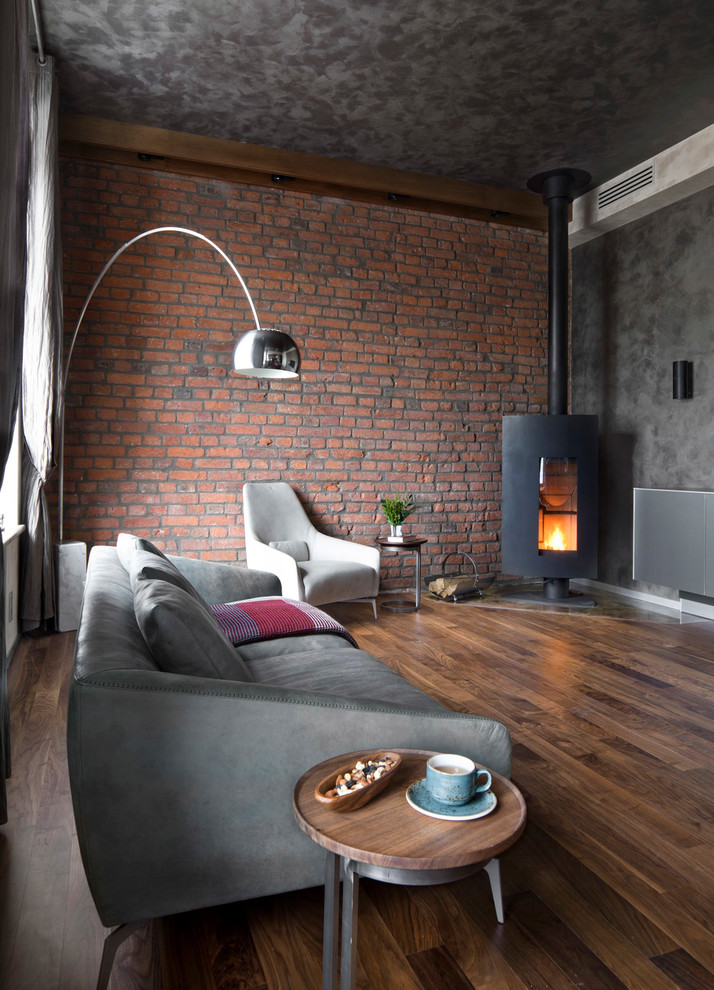 Modelo de salón abierto industrial con paredes grises, suelo de madera oscura y estufa de leña
