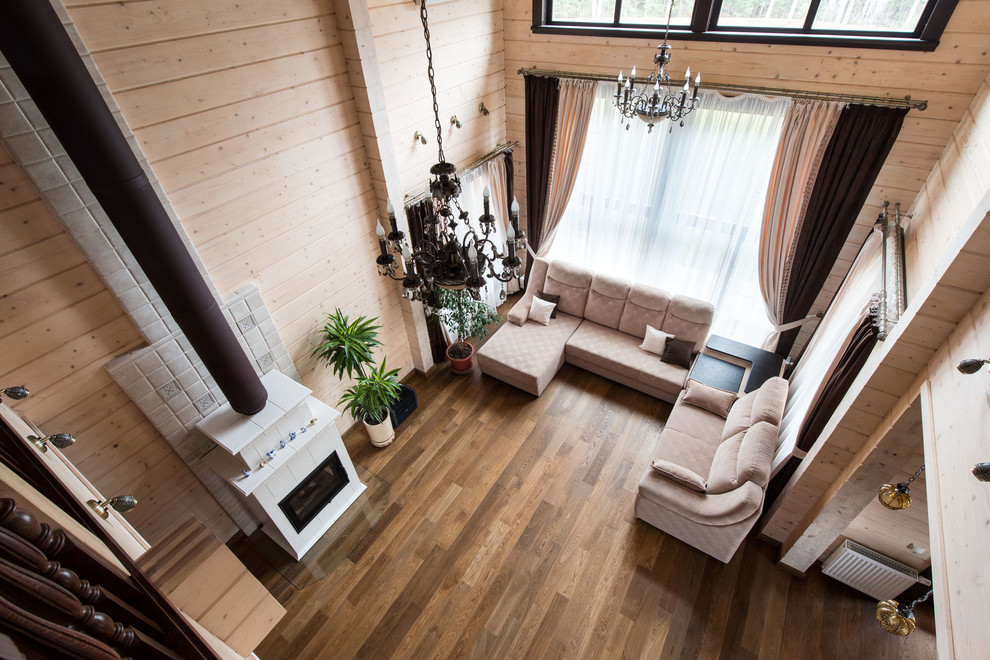 Cette image montre un salon rustique de taille moyenne et ouvert avec un mur beige, un sol en bois brun, une cheminée standard, un manteau de cheminée en carrelage et un sol marron.