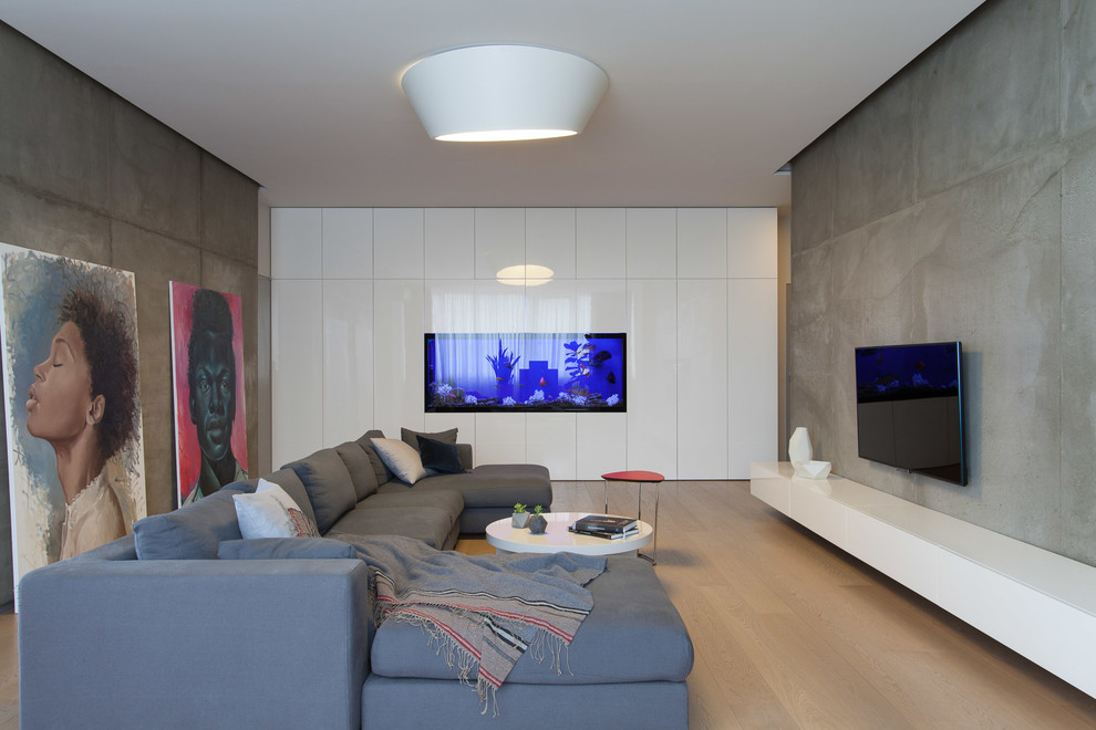 Стильный дизайн: гостиная комната в современном стиле с серыми стенами, светлым паркетным полом, телевизором на стене и бежевым полом - последний тренд