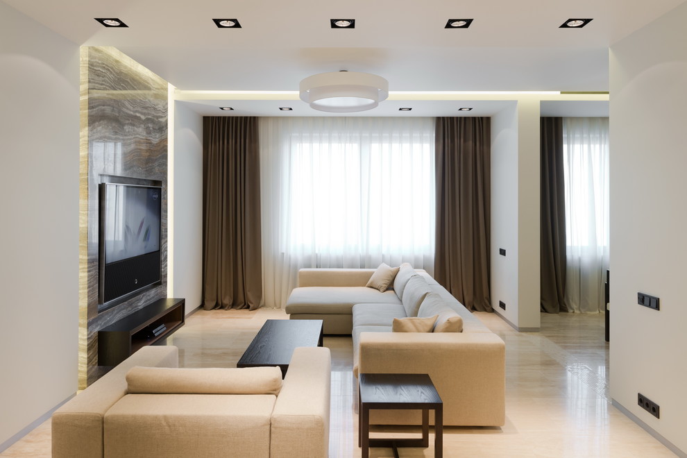 Modelo de salón actual con paredes blancas, televisor colgado en la pared y suelo beige