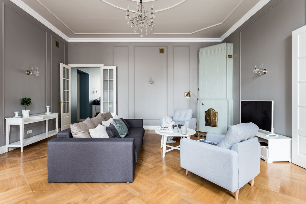 Idée de décoration pour un salon tradition fermé avec une salle de réception, un mur gris, un sol en bois brun, une cheminée d'angle, un téléviseur indépendant, un sol marron et éclairage.