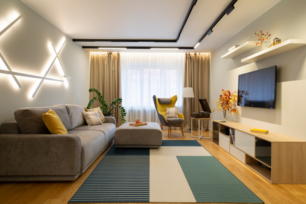 Esempio di un soggiorno design di medie dimensioni e chiuso con pareti grigie, pavimento in legno massello medio, TV a parete e pavimento marrone