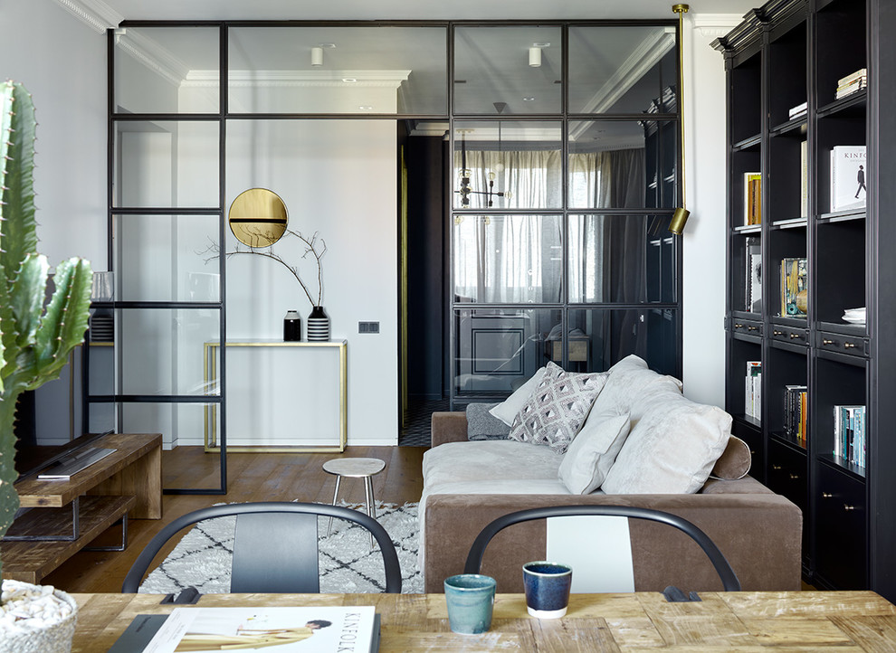 Идея дизайна: изолированная гостиная комната в современном стиле с белыми стенами, отдельно стоящим телевизором, коричневым полом, с книжными шкафами и полками и паркетным полом среднего тона без камина