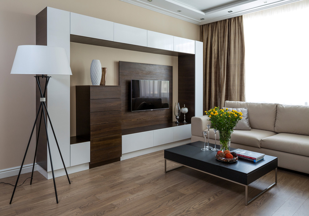 Esempio di un soggiorno design aperto con sala formale, pareti beige, pavimento in legno massello medio, TV a parete e pavimento marrone