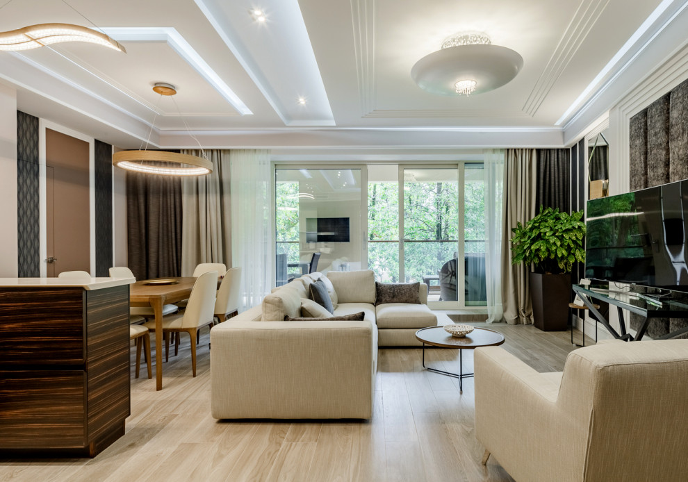 Großes, Offenes Modernes Wohnzimmer mit weißer Wandfarbe, hellem Holzboden, freistehendem TV und beigem Boden in Sonstige