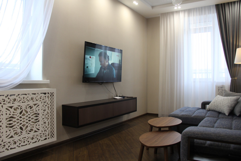 Свежая идея для дизайна: изолированная гостиная комната среднего размера в современном стиле с домашним баром, бежевыми стенами, полом из ламината, телевизором на стене и коричневым полом - отличное фото интерьера