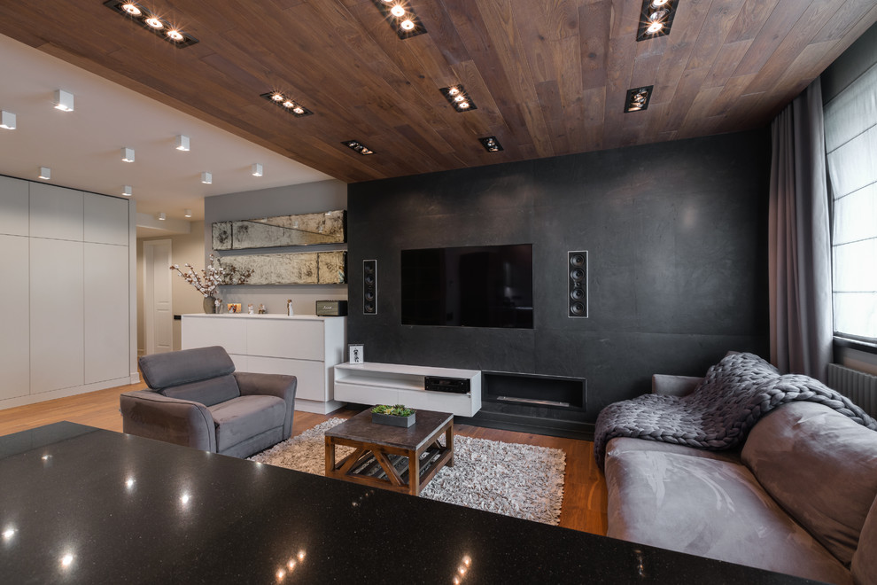 Exempel på ett modernt allrum med öppen planlösning, med svarta väggar, mellanmörkt trägolv, en bred öppen spis, en väggmonterad TV och brunt golv