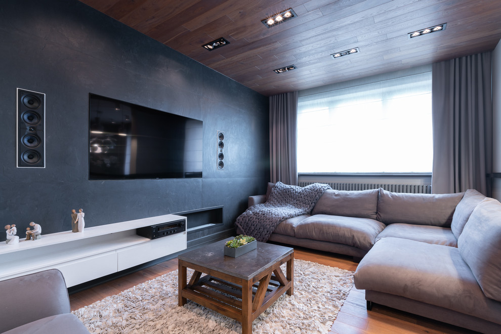 Modelo de salón actual con paredes negras, suelo de madera en tonos medios, chimenea lineal, televisor colgado en la pared y suelo marrón