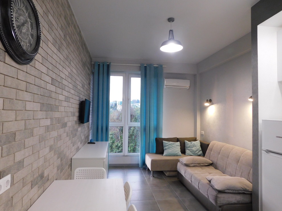 На фото: маленькая открытая гостиная комната в стиле лофт с серыми стенами, полом из керамогранита и серым полом для на участке и в саду
