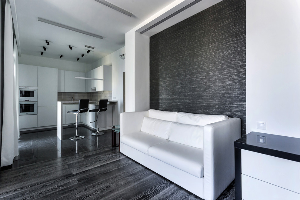 Diseño de salón abierto contemporáneo pequeño con paredes blancas, suelo de madera en tonos medios, televisor colgado en la pared y suelo negro
