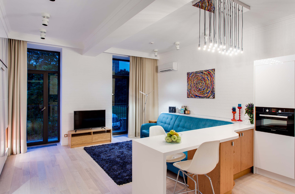 Diseño de sala de estar abierta actual sin chimenea con paredes blancas, suelo de madera clara y televisor independiente