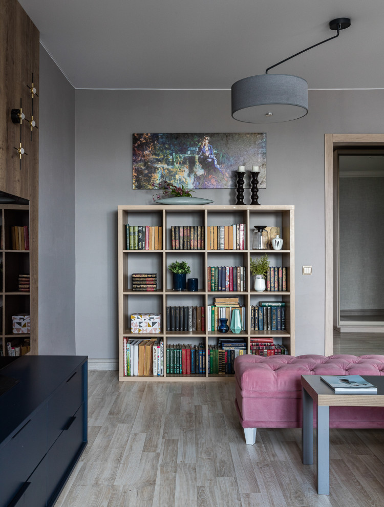 Cette photo montre un salon tendance de taille moyenne et fermé avec une bibliothèque ou un coin lecture, un mur gris, sol en stratifié, un téléviseur indépendant et un sol beige.