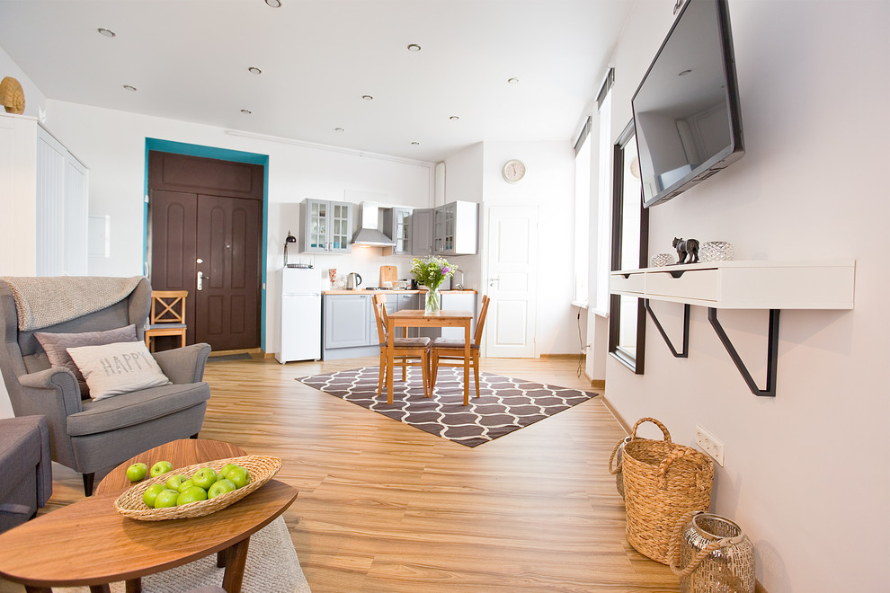 Immagine di un piccolo soggiorno design aperto con pareti bianche, pavimento in laminato, TV a parete e pavimento marrone