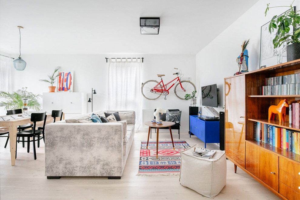 Пример оригинального дизайна: открытая гостиная комната в современном стиле с белыми стенами, светлым паркетным полом, телевизором на стене и бежевым полом