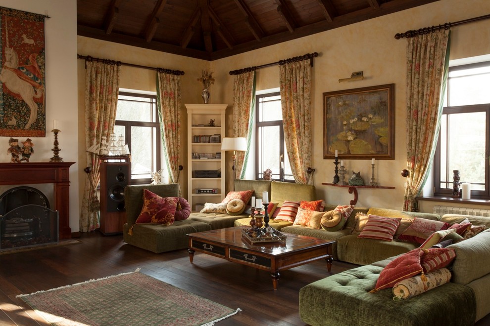 На фото: гостиная комната в средиземноморском стиле с бежевыми стенами, темным паркетным полом и стандартным камином с