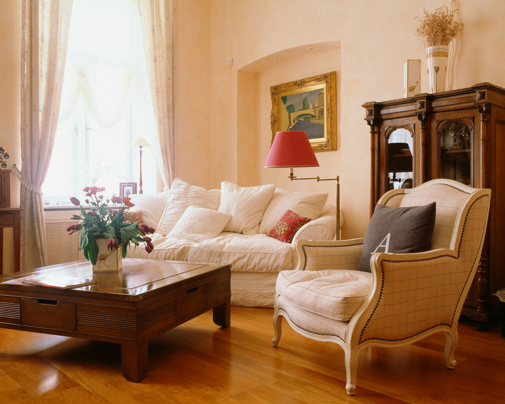 Modelo de salón tradicional con paredes beige y suelo de madera en tonos medios
