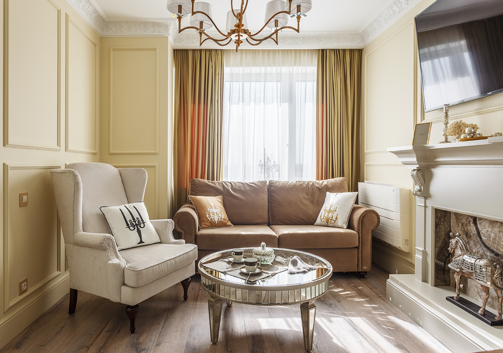 Esempio di un soggiorno tradizionale con sala formale, pareti gialle, pavimento in legno massello medio, TV a parete, camino classico e pavimento marrone