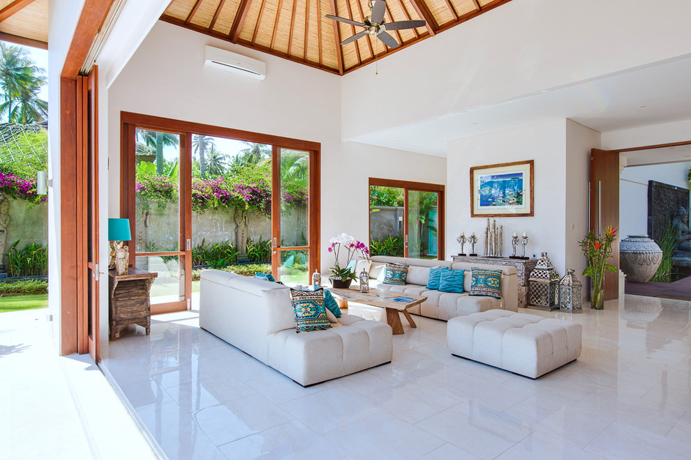 Immagine di un soggiorno tropicale aperto con pareti bianche e pavimento beige
