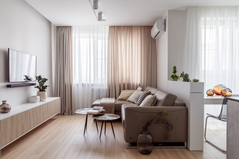 Immagine di un soggiorno minimal di medie dimensioni e aperto con pareti grigie, TV a parete, pavimento beige e parquet chiaro