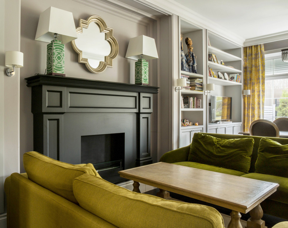 Стильный дизайн: открытая, парадная гостиная комната в стиле неоклассика (современная классика) с серыми стенами, стандартным камином и горчичным диваном - последний тренд