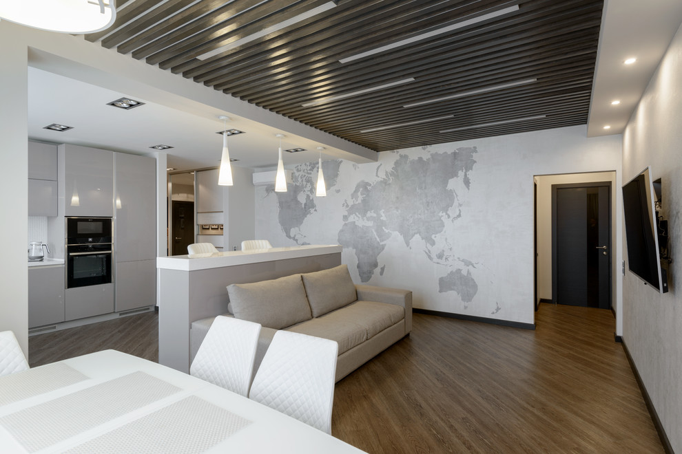 Стильный дизайн: большая открытая гостиная комната в современном стиле с серыми стенами и телевизором на стене без камина - последний тренд