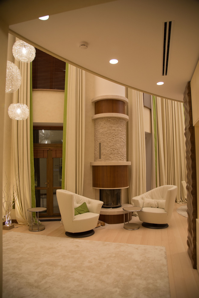 Стильный дизайн: большая парадная, открытая гостиная комната в современном стиле с бежевыми стенами, светлым паркетным полом, угловым камином, фасадом камина из дерева и бежевым полом - последний тренд