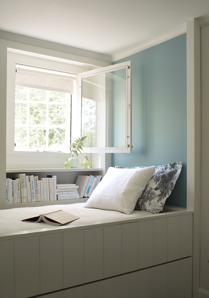 На фото: гостиная комната в морском стиле с с книжными шкафами и полками и синими стенами с