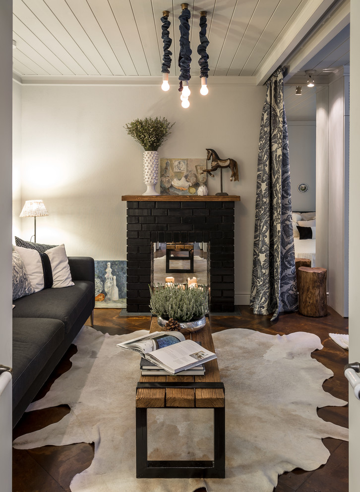 На фото: маленькая гостиная комната с серыми стенами, стандартным камином, фасадом камина из кирпича и телевизором на стене для на участке и в саду