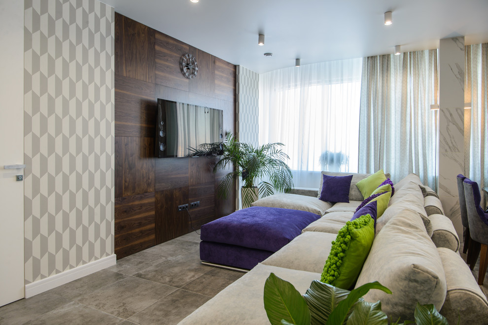 Пример оригинального дизайна: открытая гостиная комната в современном стиле с телевизором на стене и серыми стенами