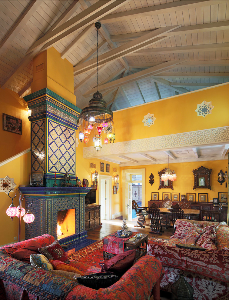 Источник вдохновения для домашнего уюта: огромная открытая гостиная комната в восточном стиле с желтыми стенами, стандартным камином, фасадом камина из плитки и отдельно стоящим телевизором