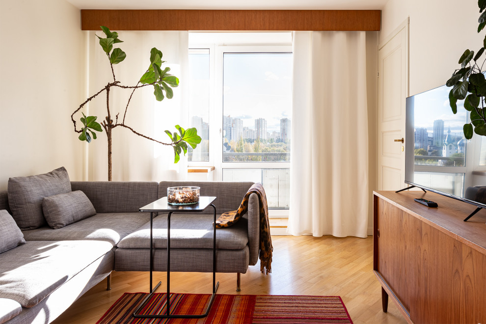 Ispirazione per un soggiorno minimalista di medie dimensioni con libreria, pareti bianche, pavimento in legno massello medio e pavimento beige