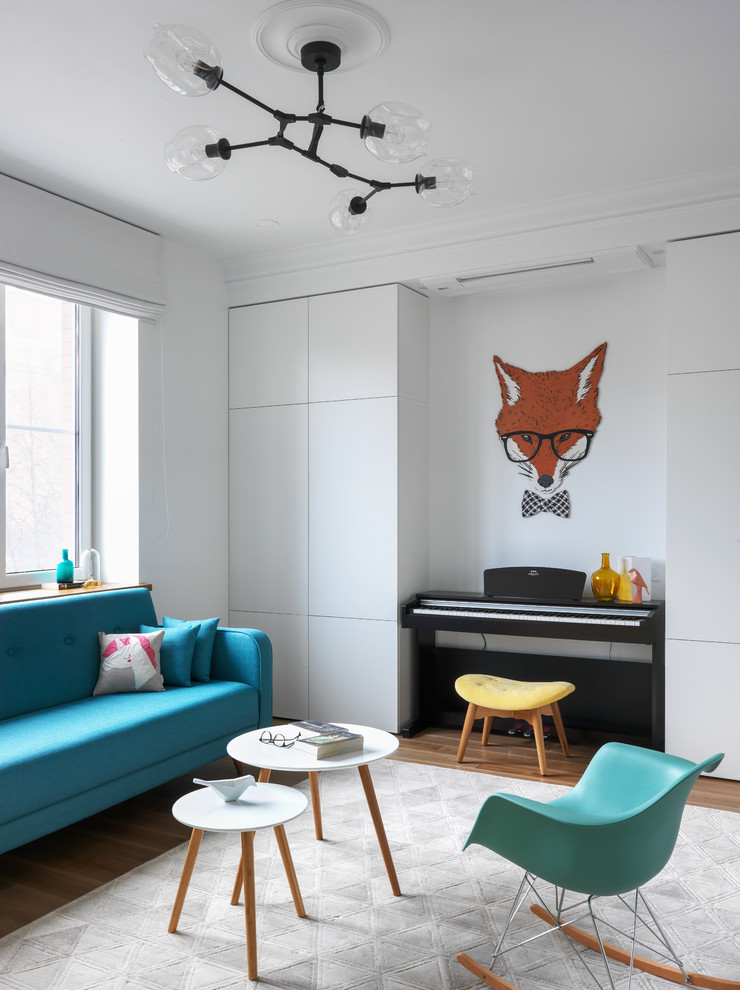 Стильный дизайн: гостиная комната в современном стиле с белыми стенами, паркетным полом среднего тона, коричневым полом и синим диваном - последний тренд