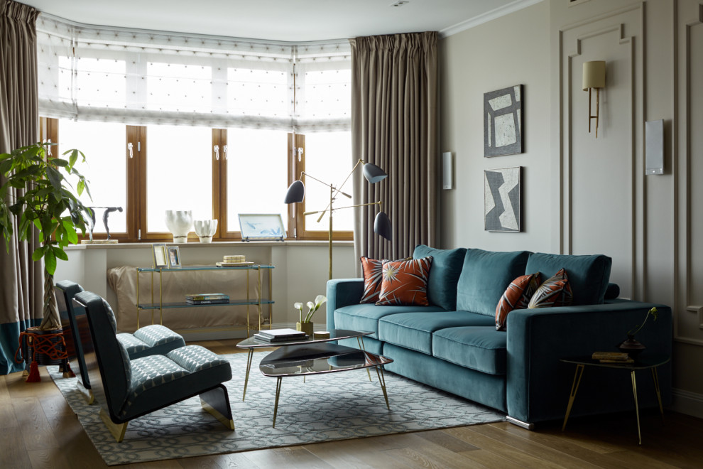 На фото: гостиная комната в стиле неоклассика (современная классика) с бежевыми стенами, темным паркетным полом, коричневым полом и синим диваном с