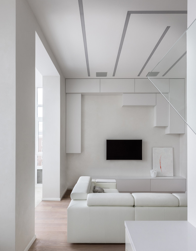 Foto di un soggiorno design di medie dimensioni e aperto con pareti bianche, pavimento in legno massello medio, nessun camino, TV a parete e pavimento marrone