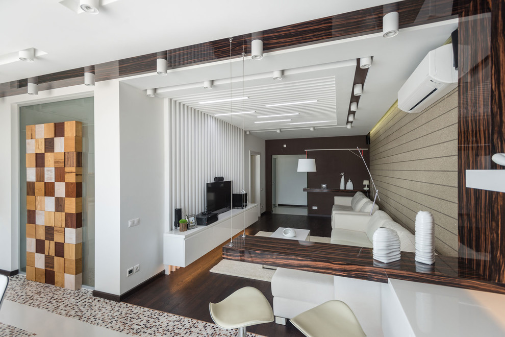 Abgetrenntes Modernes Wohnzimmer mit dunklem Holzboden, freistehendem TV und beiger Wandfarbe in Sonstige