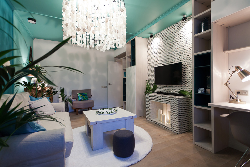 Imagen de salón cerrado mediterráneo pequeño con paredes azules, suelo de madera clara, chimenea lineal, marco de chimenea de baldosas y/o azulejos y televisor colgado en la pared