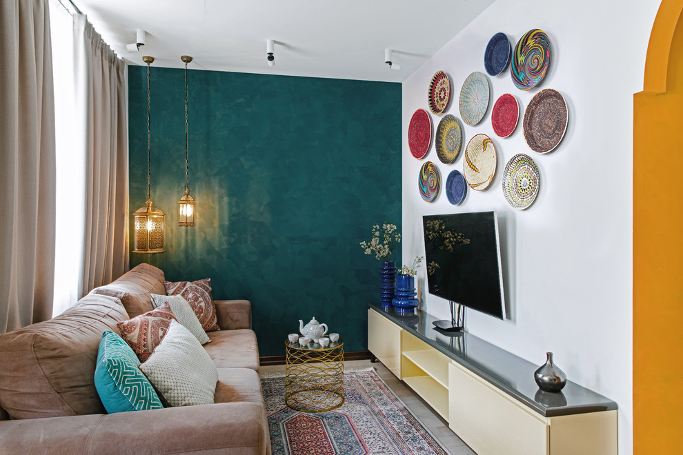 На фото: гостиная комната в стиле фьюжн с телевизором на стене, синими стенами и коричневым диваном без камина с