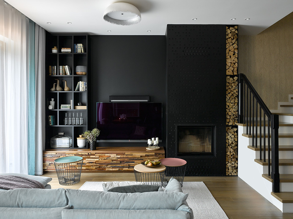 Medium sized contemporary open plan games room in Moscow with black walls, medium hardwood flooring, a standard fireplace, a metal fireplace surround, a wall mounted tv, a reading nook and feature lighting.