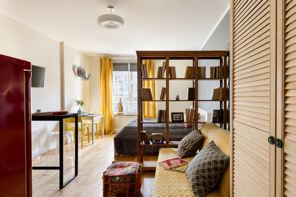 Idee per un piccolo soggiorno bohémian stile loft con libreria, pareti beige, pavimento in laminato, nessun camino e TV a parete