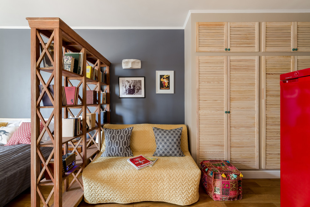 Imagen de biblioteca en casa tipo loft ecléctica pequeña sin chimenea con paredes beige, suelo laminado y televisor colgado en la pared